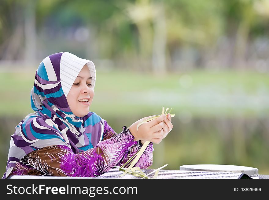 A woman weaving bamboo mats while relaxing in the park