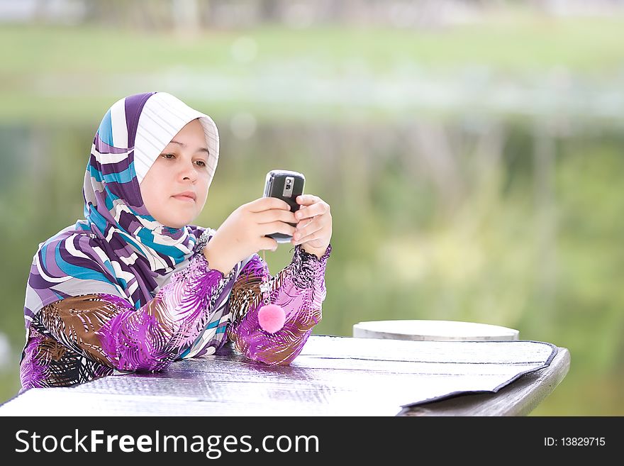 Asean Muslim Women playing her mobile phone. Asean Muslim Women playing her mobile phone