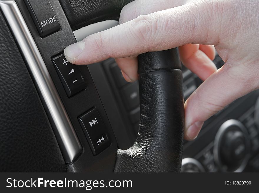 Finger pushing increase volume button on the steering wheel