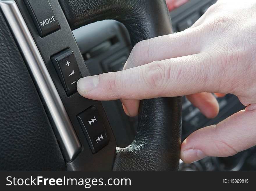 Finger pushing increase volume button on the steering wheel. Finger pushing increase volume button on the steering wheel