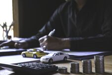 Car Insurance And Car Service. Businessman With Stack Of Coins And Toy Car, Business And Financial Concept Royalty Free Stock Images