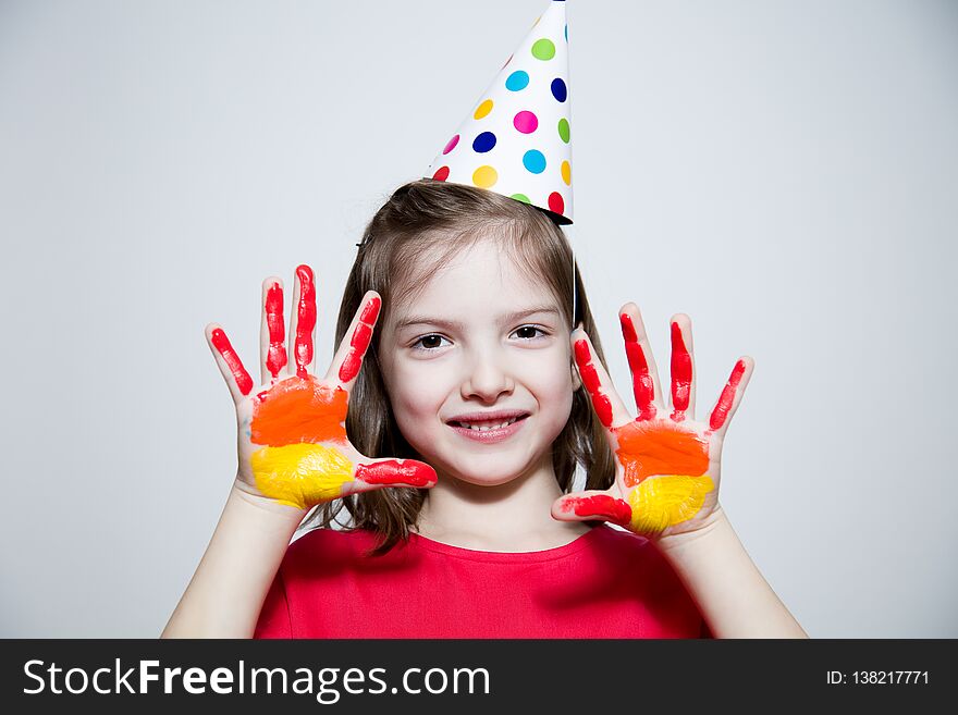 Child in a bright dress and cap, showing her hands painted in bright colors. Child in a bright dress and cap, showing her hands painted in bright colors