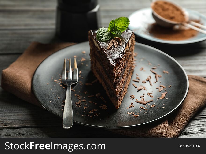 Plate with slice of chocolate cake and fork on wooden table