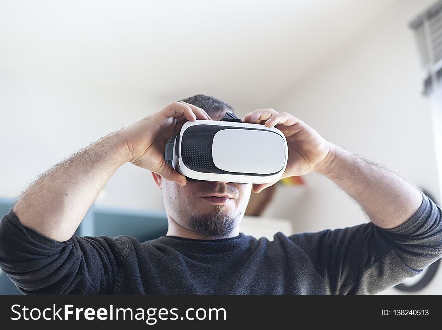 young man using virtual reality headset, technology, male, vr, device, 3d, adult, glasses, modern, innovation, entertainment, fun, video, digital, futuristic, experience, business, excited, vision, caucasian, simulation, hi-tech, enjoying, white, contemporary, casual, person, watch, indoors, home, play, background, beard, handsome, smile, videogame, shirt, startup, wearable, gear, looking, activity, display, comfortable