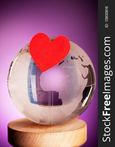 Globe with red heart shot on violet backgorund. Globe with red heart shot on violet backgorund