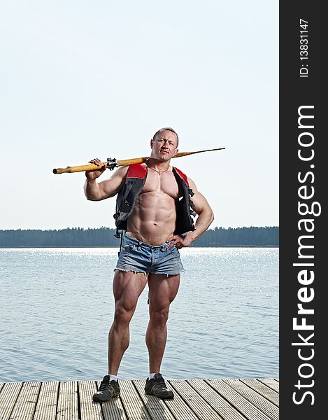 Muscular Man with oar at lake