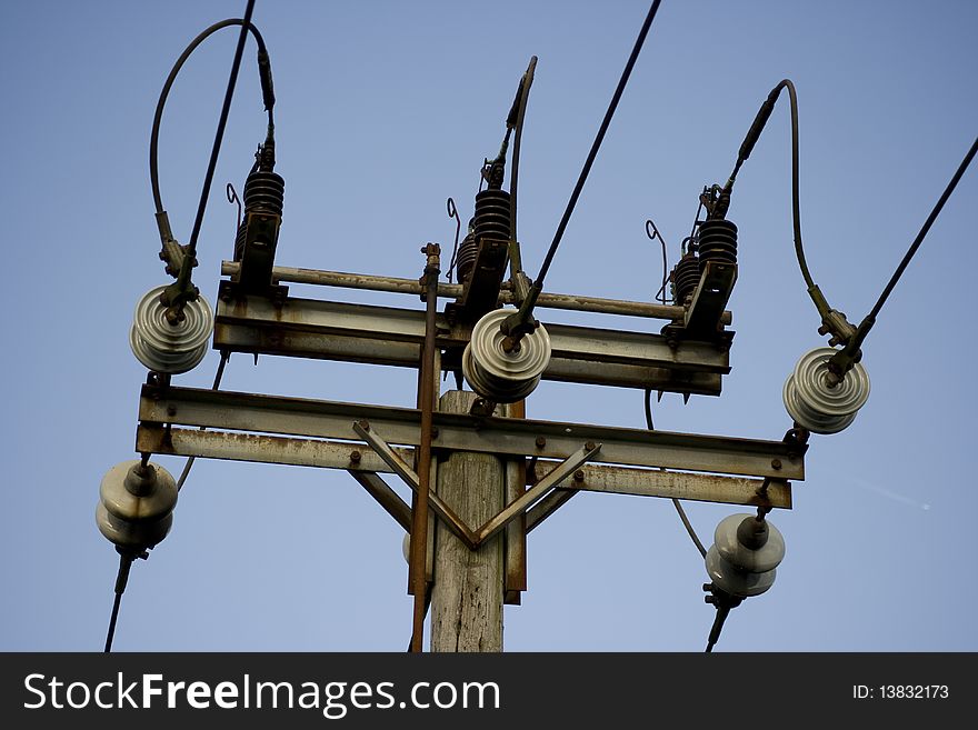 A upwards close up view of a Electric pole against a blue sky.