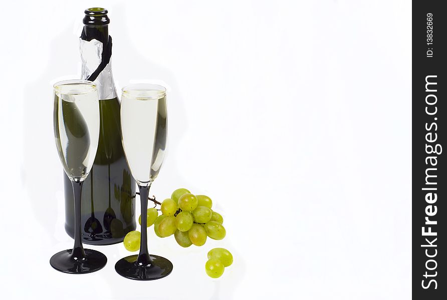 Glasses, bottle of champagne and grapes cluster on white background