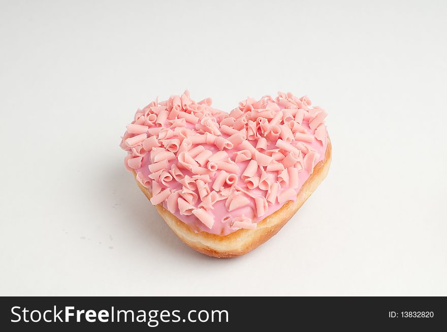 Heart shaped pink doughnut placed on white background