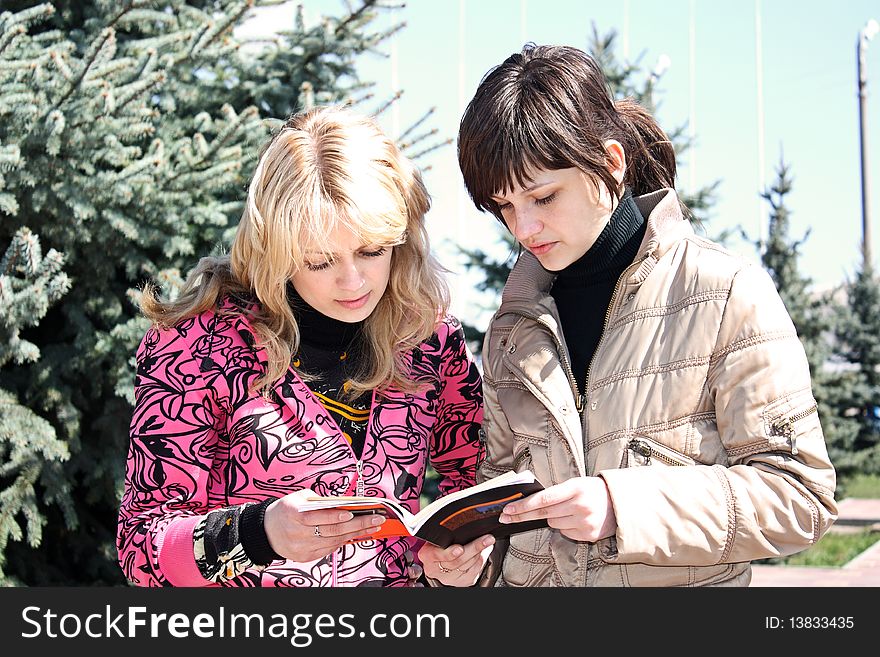 Two girls read the book in a park