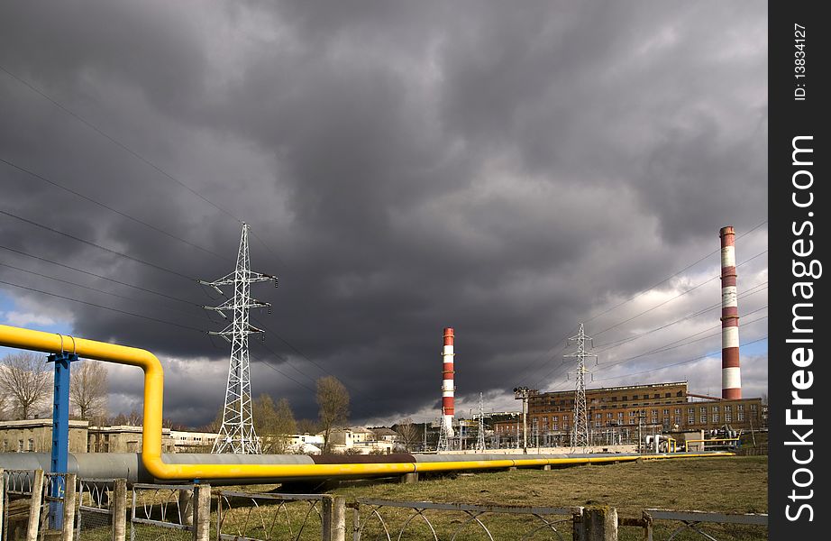 Smokestack with gas line on power station with dark clouds. Smokestack with gas line on power station with dark clouds