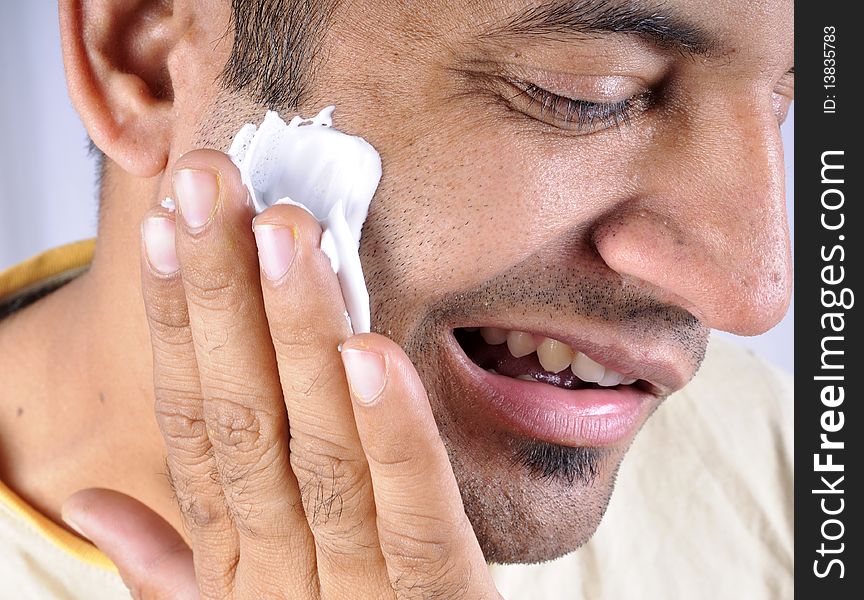 Rubbing shaving cream on face.