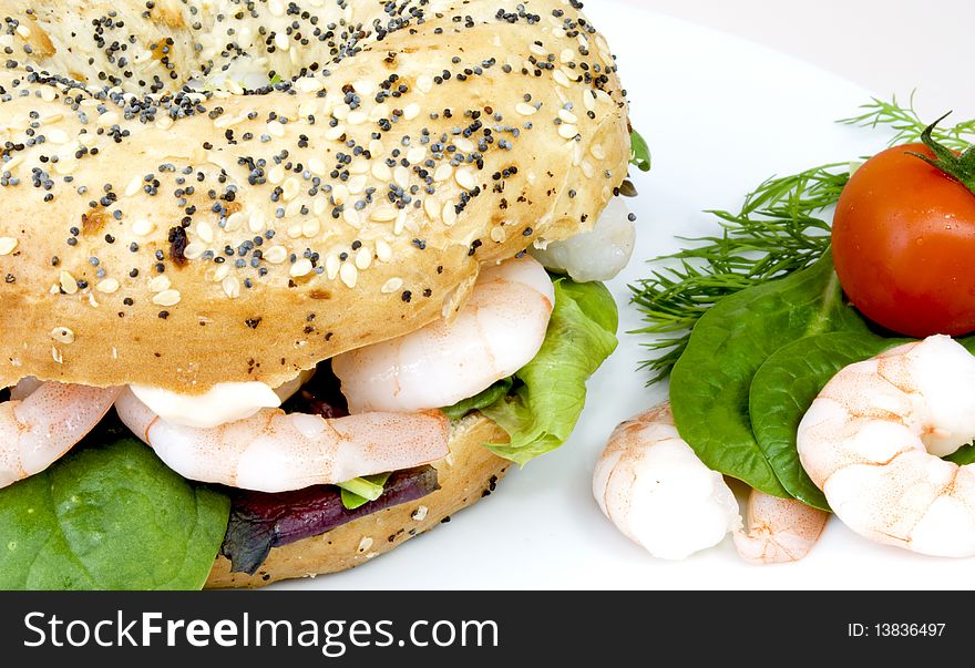 Bagel with salad, prawns and cocktail sauce, tomato and salad as decoration on the side. Bagel with salad, prawns and cocktail sauce, tomato and salad as decoration on the side