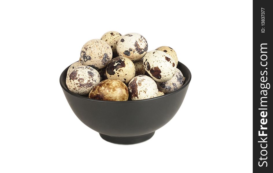 Quail eggs in a bowl of black on a white background