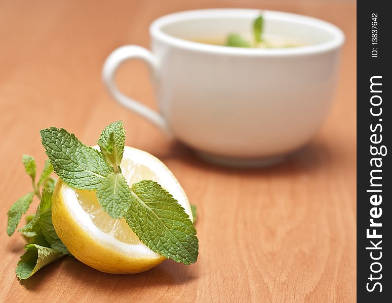 Tea with mint and lemon on a wood background