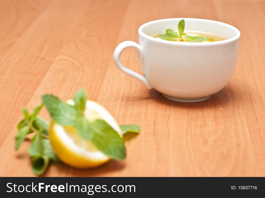 Tea with mint and lemon on a wood background