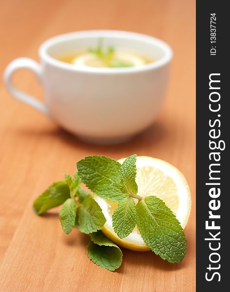 Tea with mint and lemon on a wood background