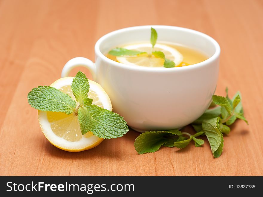 Tea with mint and lemon on a wood background