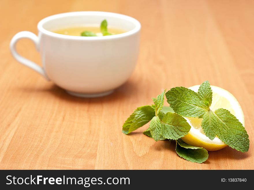 Tea with mint and lemon on a wood background