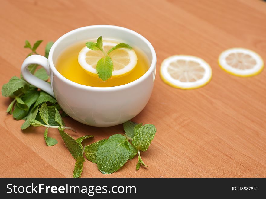 Tea with mint and lemon on a wood background