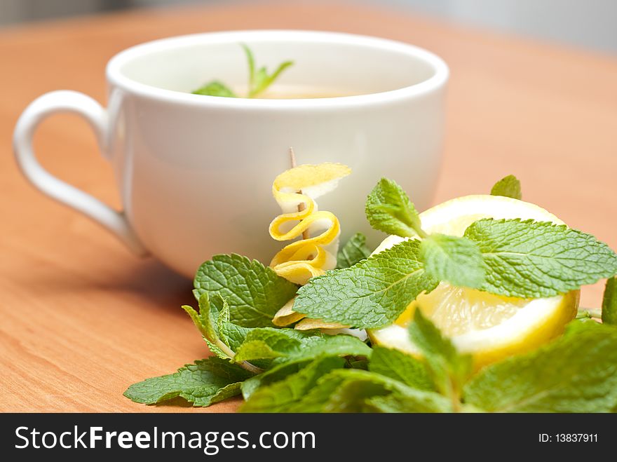 Tea with mint and lemon on a wood background