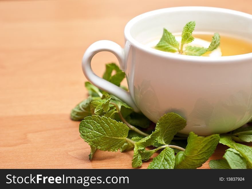 Tea with mint and lemon on a wood background