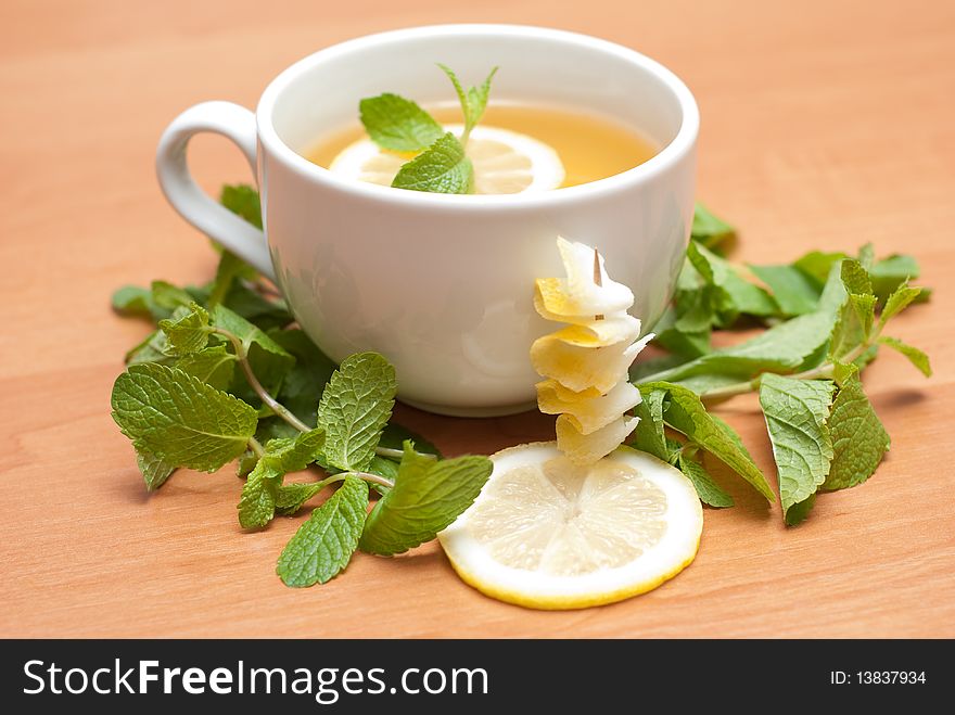 Tea with mint and lemon on a wood background