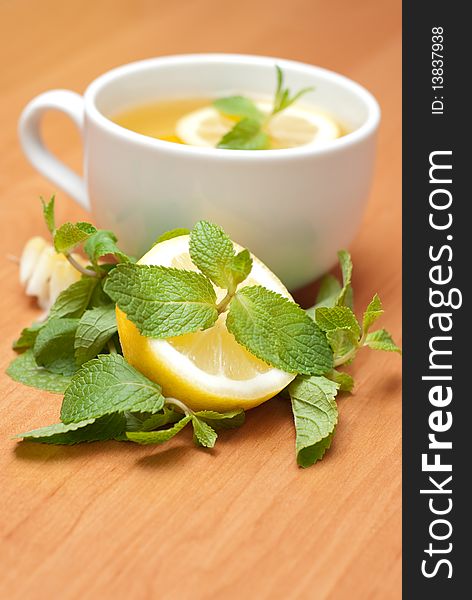 Tea with mint and lemon on a wood background