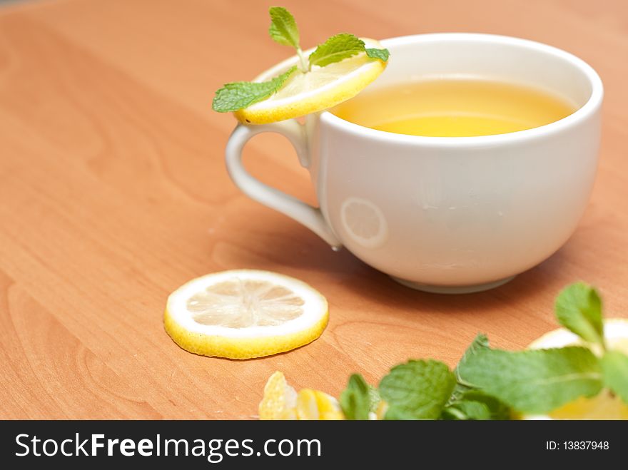 Tea with mint and lemon on a wood background