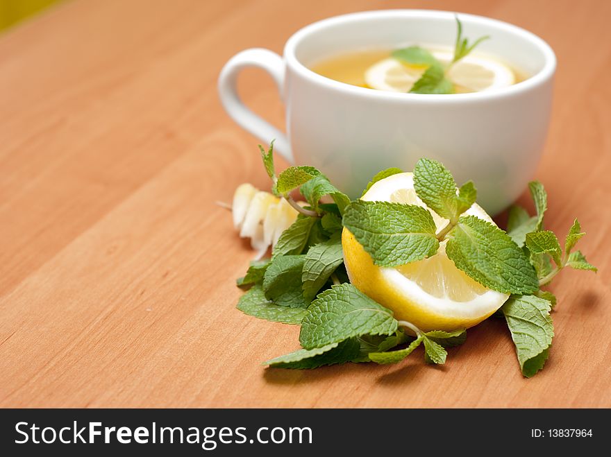 Tea with mint and lemon on a wood background