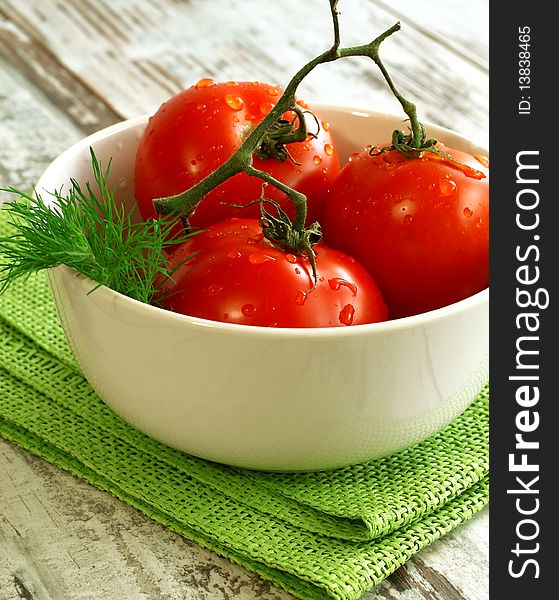 tomatoes with water drops in bowl on wooden boards