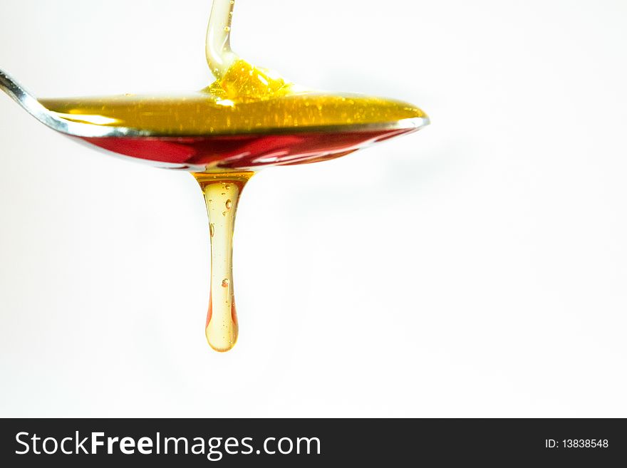 Honey pouring in a spoon on white background. Honey pouring in a spoon on white background