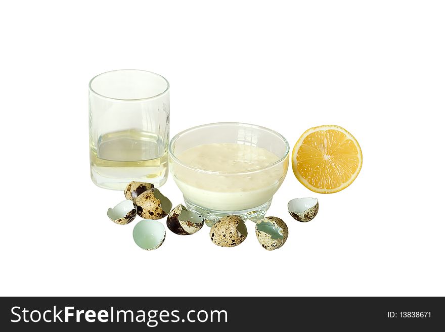 Mayonnaise in transparent plate around shell of quail eggs, cut lemon and glass with oil. Mayonnaise in transparent plate around shell of quail eggs, cut lemon and glass with oil