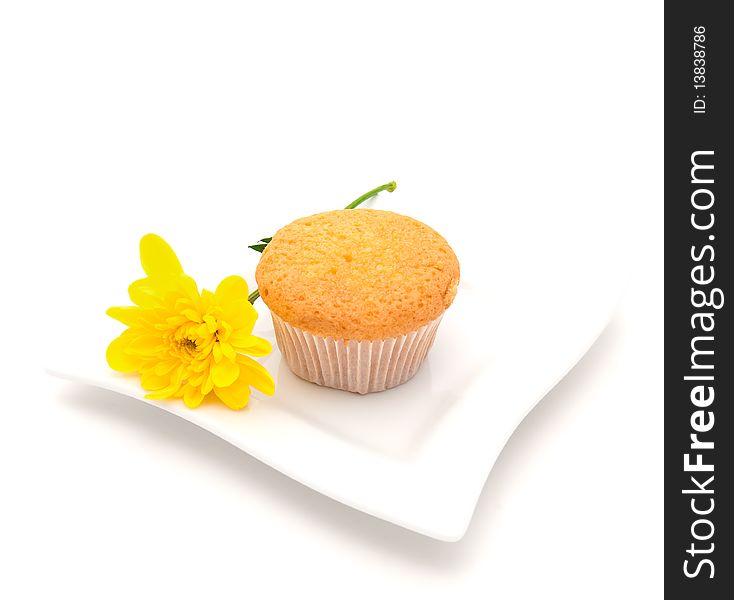Gentle vanilla cake on a white plate and a yellow camomile. Gentle vanilla cake on a white plate and a yellow camomile