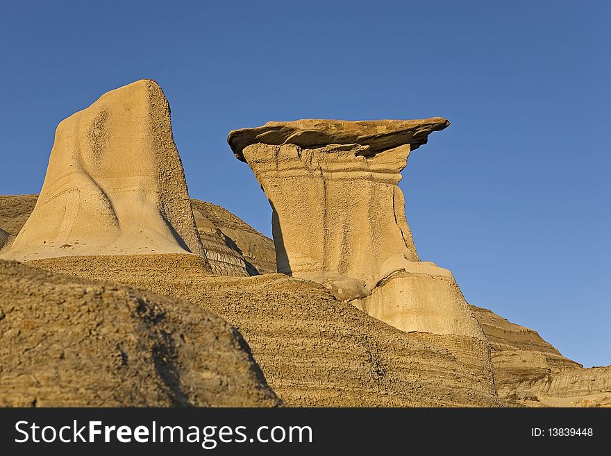 Badlands hoodoos with blue sky background in the late afternoon sun. Badlands hoodoos with blue sky background in the late afternoon sun