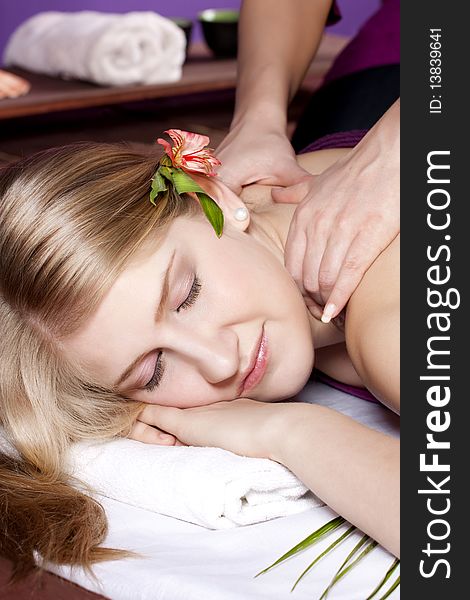 Beautiful woman on massage table with flower in hair