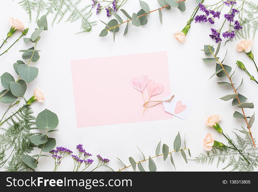 Flowers composition. Paper blank, carnation flowers, eucalyptus branches on pastel background. Flat lay, top view, copy spaceFlat