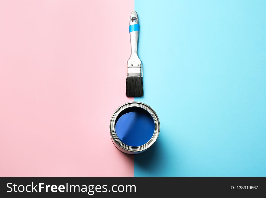 Open paint can and brush on color background, top view