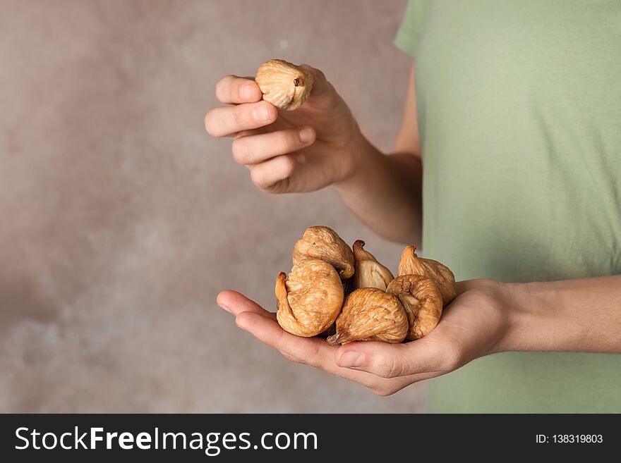 Woman holding handful of dried figs on color background, space for text.