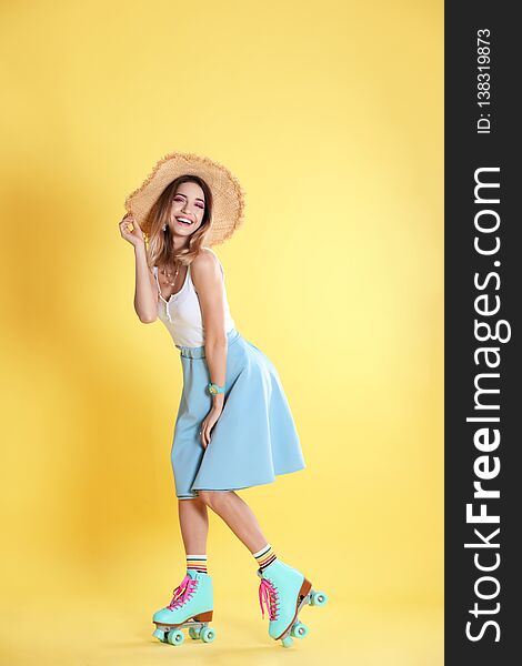 Young woman with retro roller skates on color background