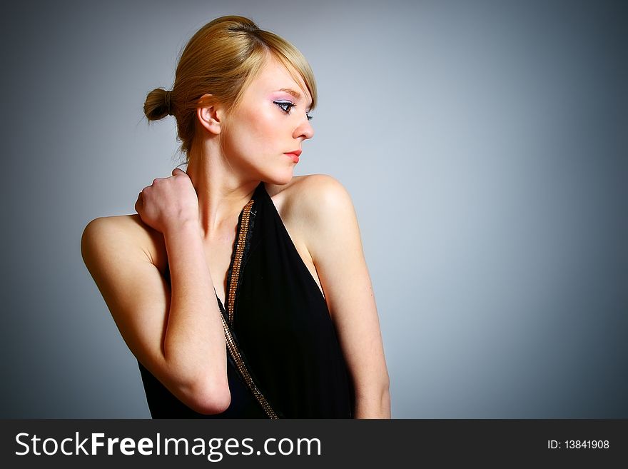 Young woman posing on grey background in black dress. Young woman posing on grey background in black dress