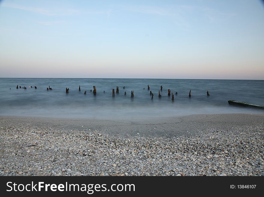 Sea at night with moon and wooden poles