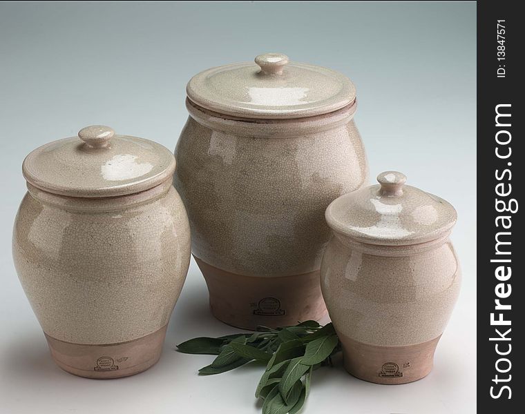 Grouping three clay pots with lids on a gray background