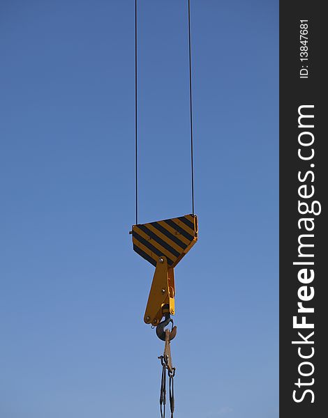 The hook of the crane on blue sky background. The hook of the crane on blue sky background