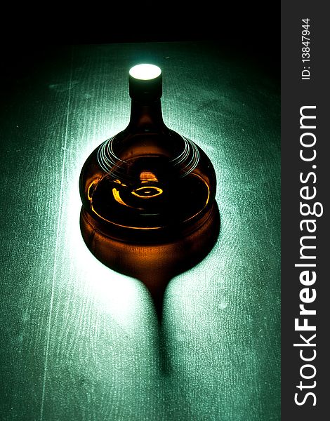 Amber bottle in green spotlight on the floor