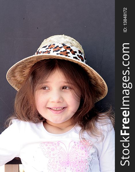 Pretty little girl smiling wearing a straw hat and black background. Pretty little girl smiling wearing a straw hat and black background