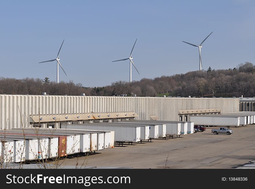 Wind turbines provide the backdrop to a shipping terminal. Renewable energy sources, such as wind power, are increasingly being utilized to provide industries with the large amounts of power and electricity they need to run.