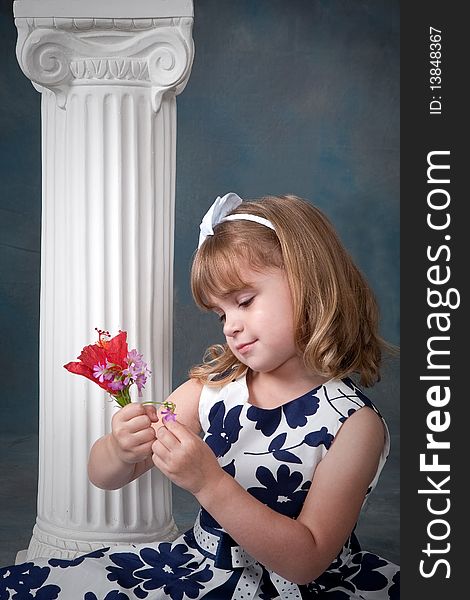 Pretty little girl with blond hair pulling petals off a flower. Pretty little girl with blond hair pulling petals off a flower.