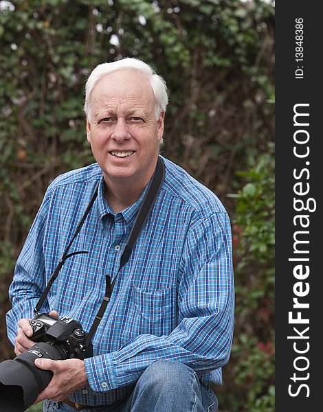 Senior man wearing blue shirt and holding a camera outdoors. Senior man wearing blue shirt and holding a camera outdoors.
