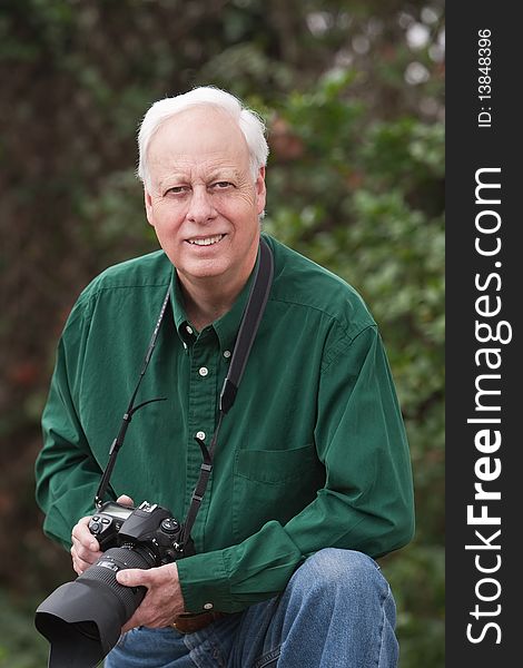 Senior man wearing blue shirt and holding a camera outdoors. Senior man wearing blue shirt and holding a camera outdoors.